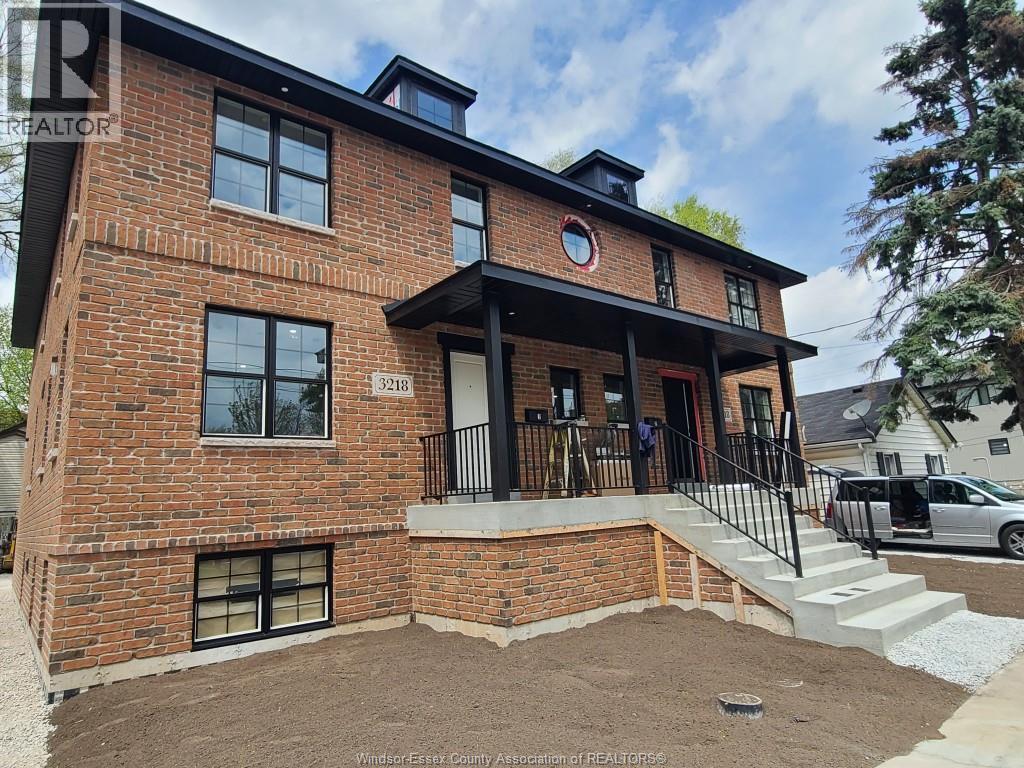 A red brick house with a black metal railing on the porch.