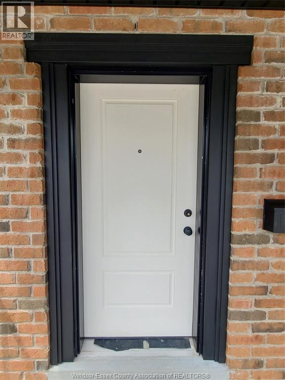 A white door with a black frame is set in a brick wall.