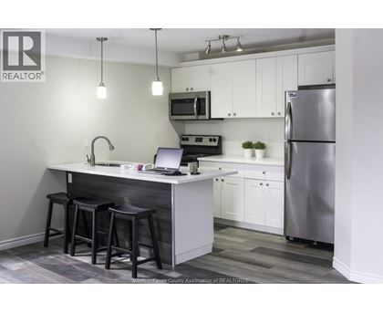 A kitchen with a bar stool and a laptop on the counter.