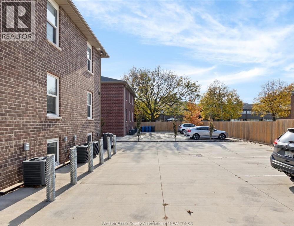 A parking lot with a building on the left and cars parked in the lot.