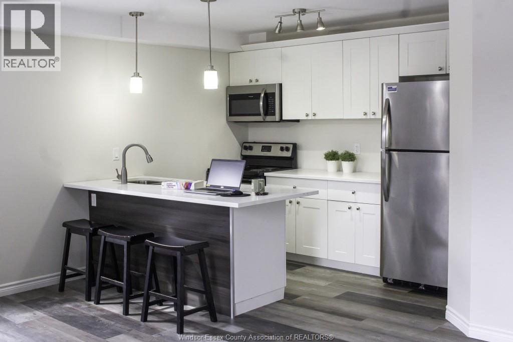 A kitchen with a bar stool and a laptop on the counter.