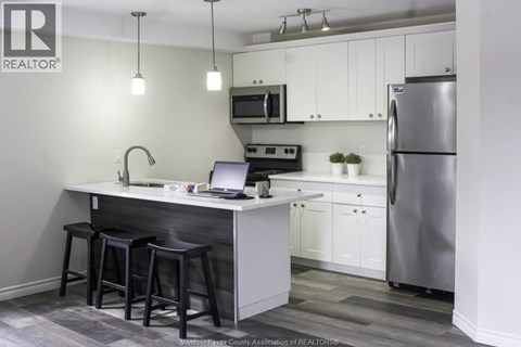 A kitchen with a bar stool and a laptop on the counter.