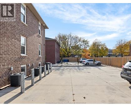 A parking lot with a building on the left and cars parked in the lot.