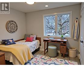 A bedroom with a bed, desk, and window.