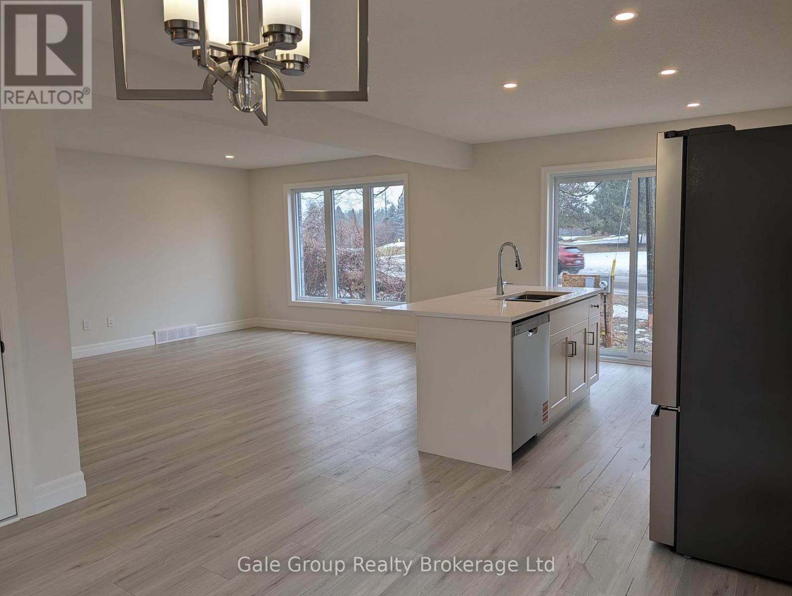 A spacious kitchen with a refrigerator, sink, and cabinets.