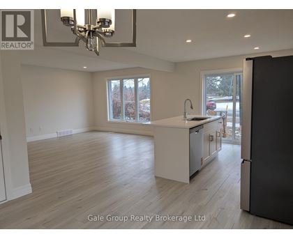 A spacious kitchen with a refrigerator, sink, and cabinets.