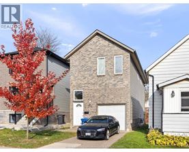 A black car is parked in front of a brick house.