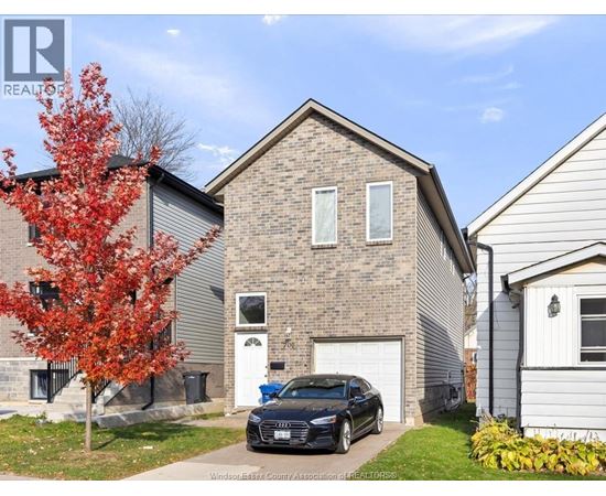 A black car is parked in front of a brick house.