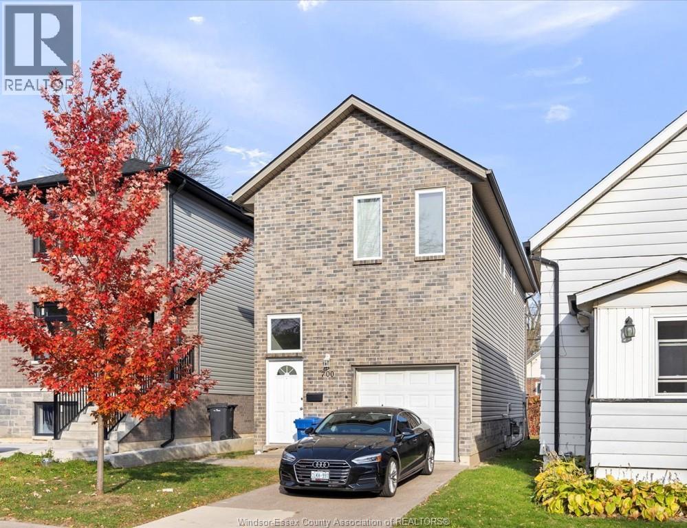 A black car is parked in front of a brick house.