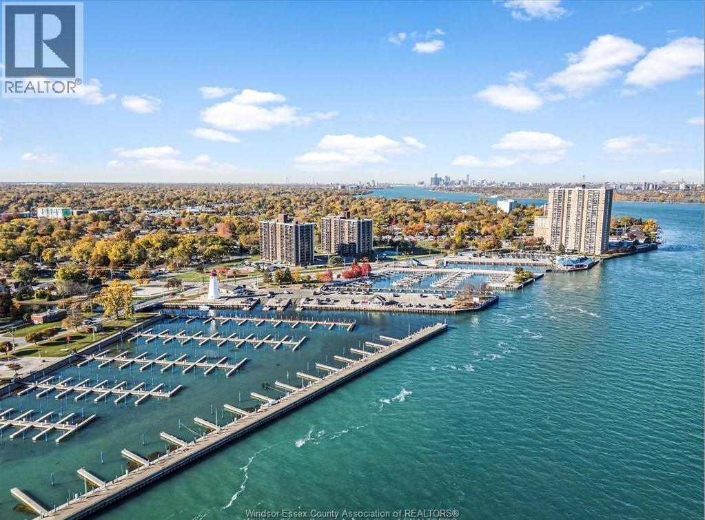 A marina with boats docked in the foreground and a city skyline in the background.