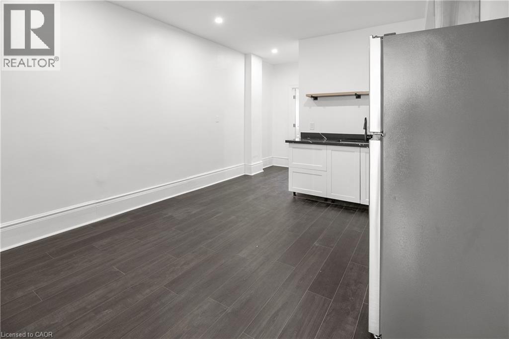A spacious kitchen with white cabinets and a wooden floor.