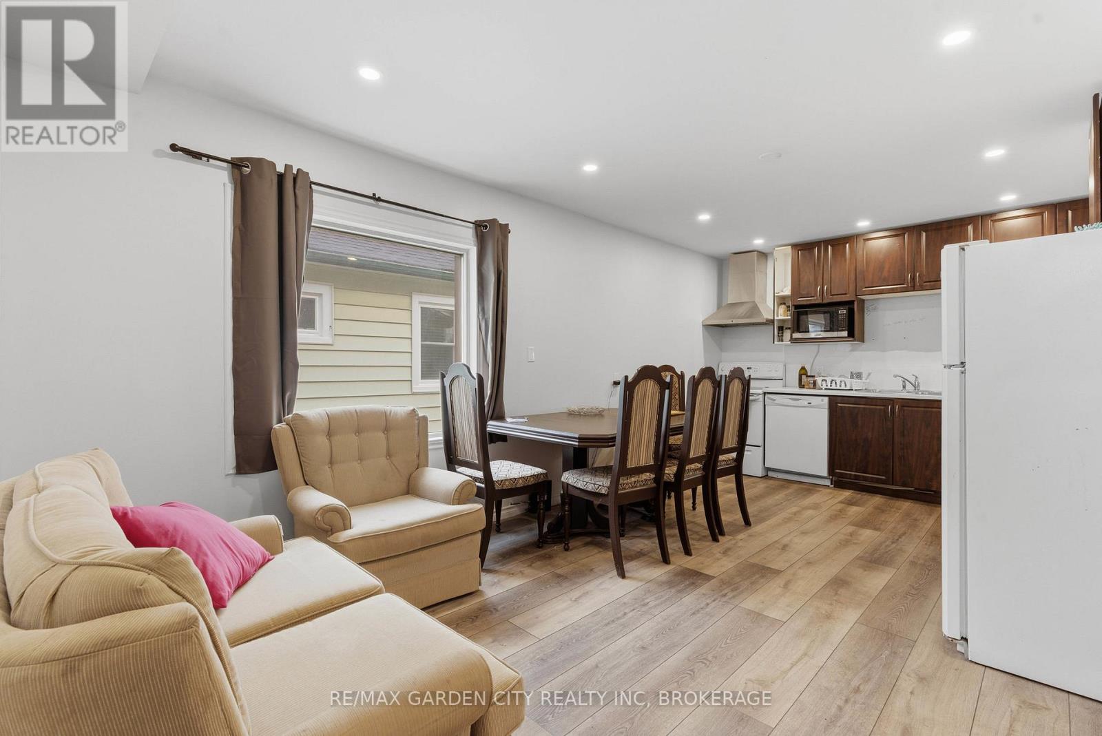 A living room with a couch, chairs, and a dining table.
