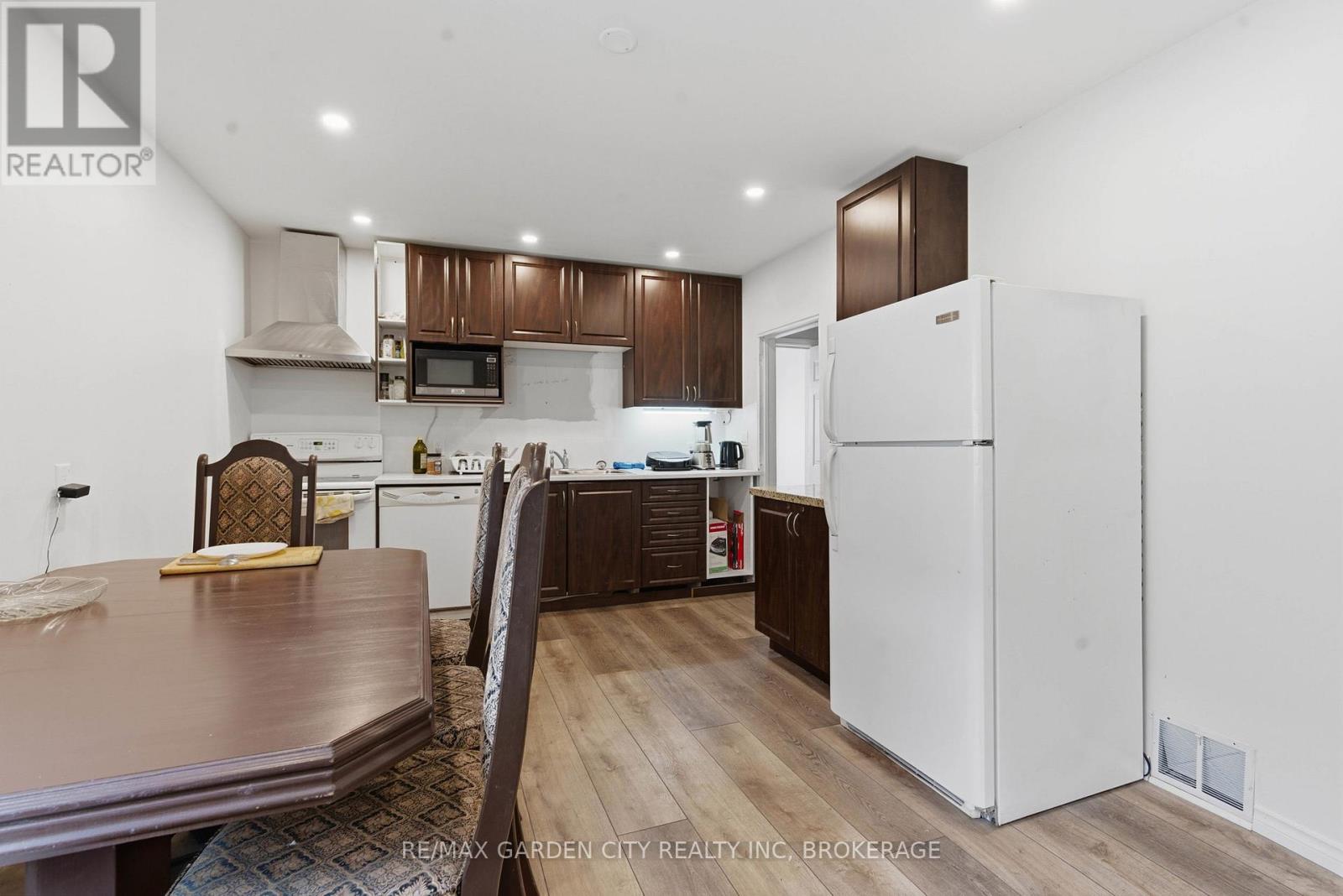 A kitchen with a white refrigerator and brown cabinets.