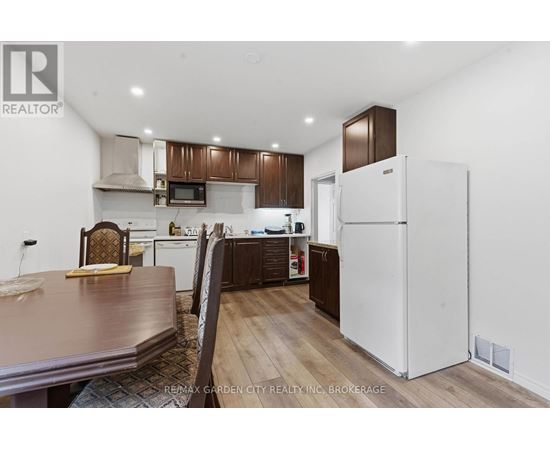 A kitchen with a white refrigerator and brown cabinets.