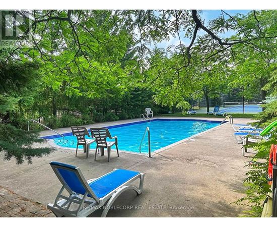 A pool surrounded by trees and chairs.