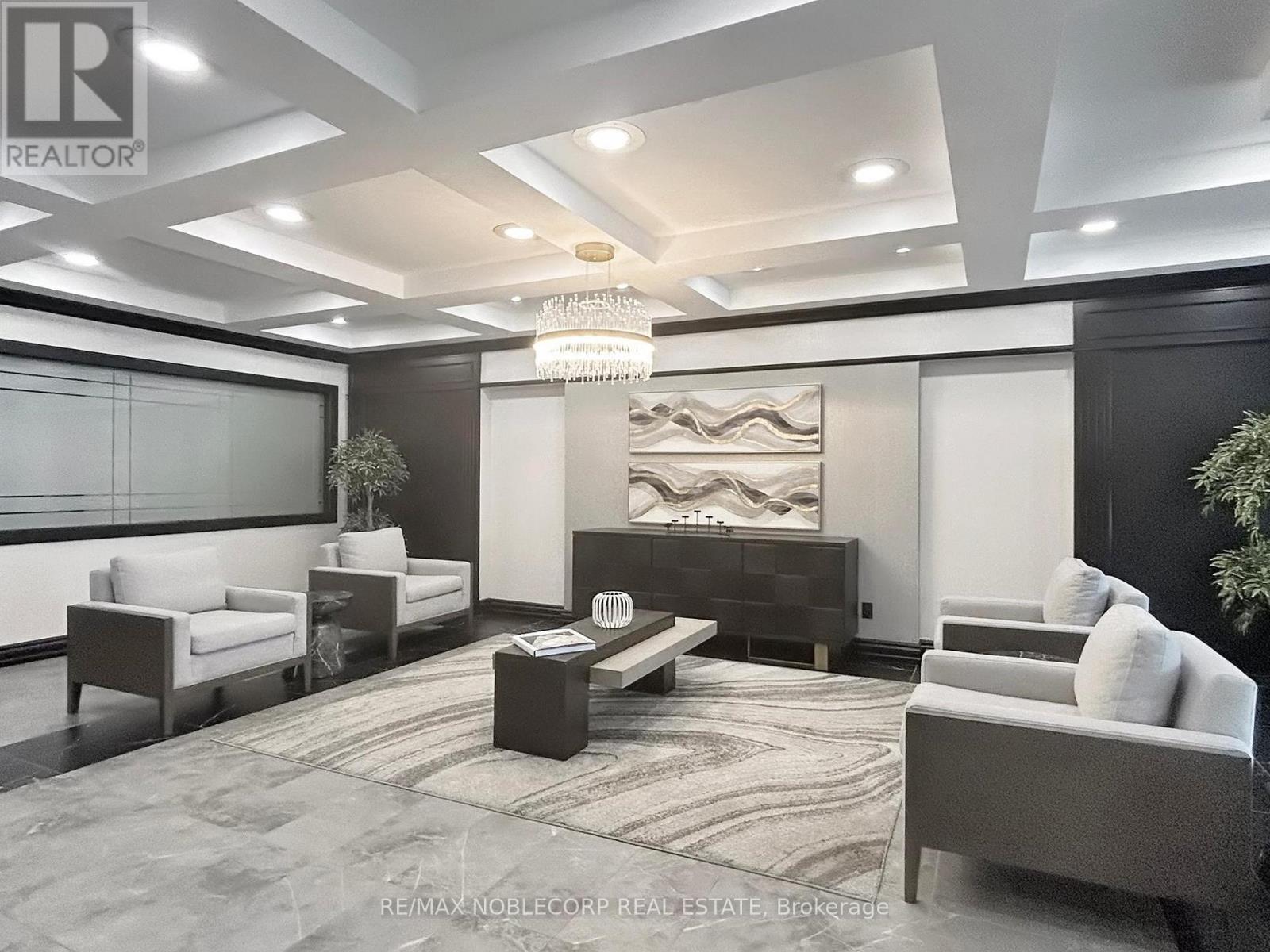 A modern living room with a large chandelier and a dark wood entertainment center.