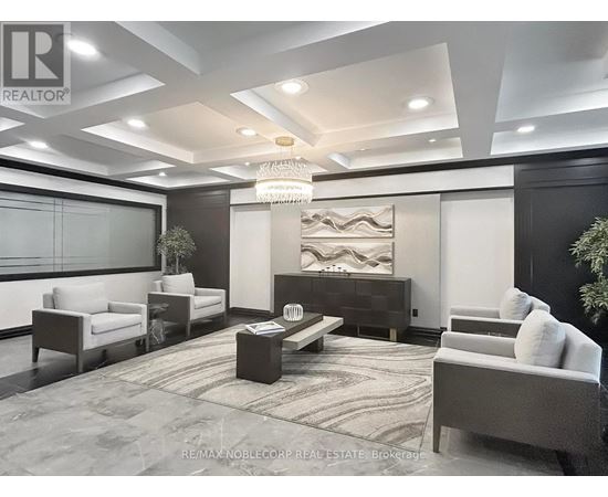 A modern living room with a large chandelier and a dark wood entertainment center.
