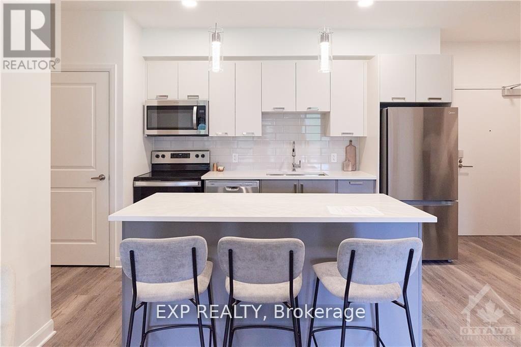 A kitchen with white cabinets and a white island with two chairs.