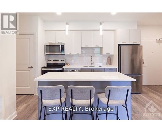 A kitchen with white cabinets and a white island with two chairs.