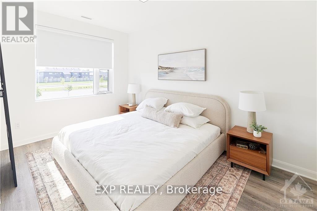 A bedroom with a large bed, a nightstand with a lamp, and a framed picture on the wall.