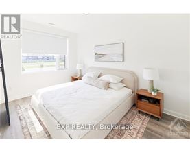 A bedroom with a large bed, a nightstand with a lamp, and a framed picture on the wall.
