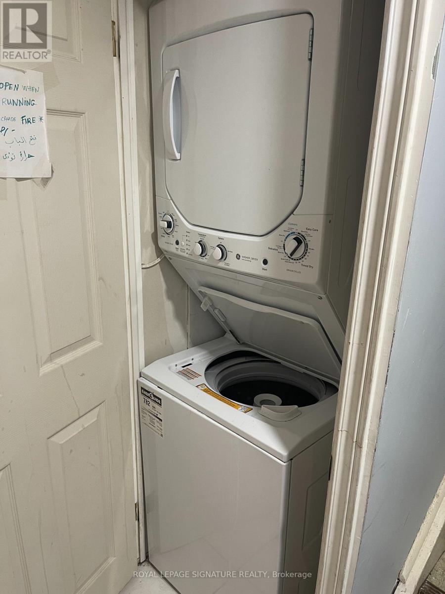 A white dryer is in a small space next to a white door.