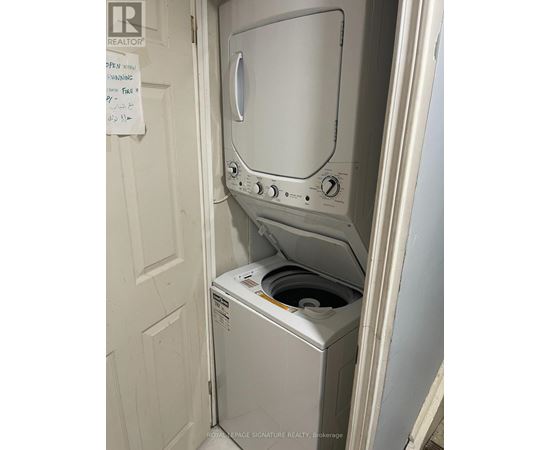 A white dryer is in a small space next to a white door.