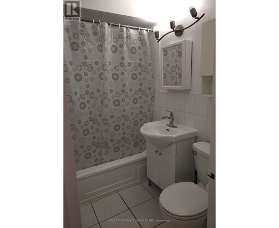 A bathroom with a shower curtain, toilet, and sink.