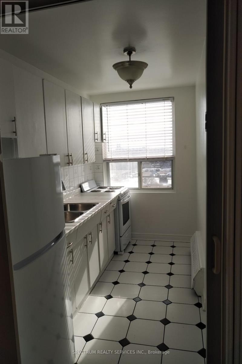 A kitchen with white cabinets and black and white tiles.