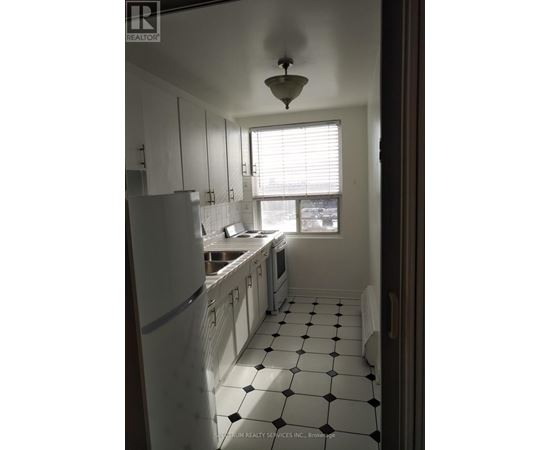A kitchen with white cabinets and black and white tiles.