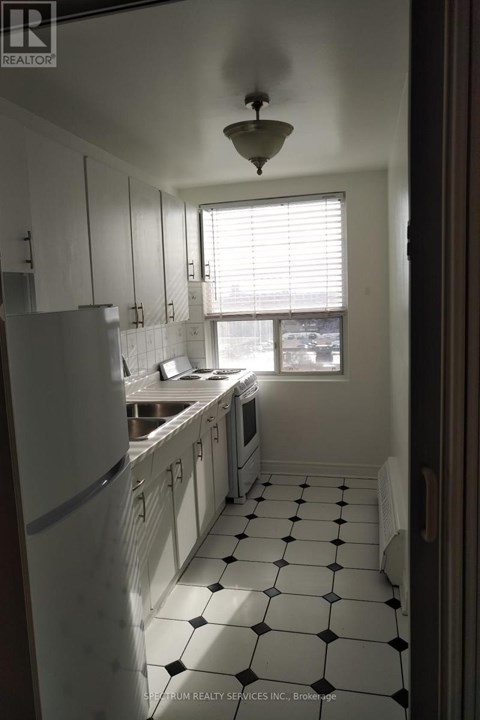 A kitchen with white cabinets and black and white tiles.