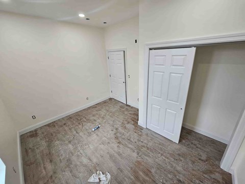 A room with a white door and a brown floor.