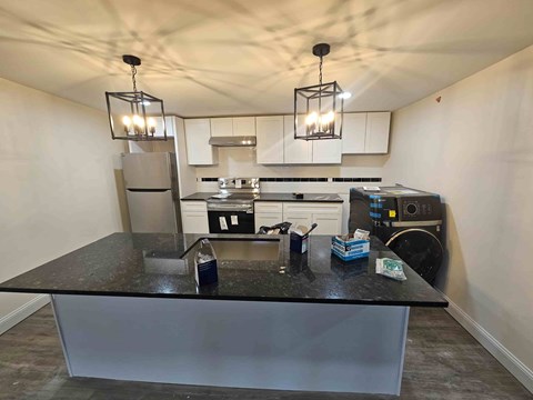 A kitchen with a black countertop and a refrigerator.