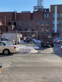 A car is parked on the side of a street with a building in the background.