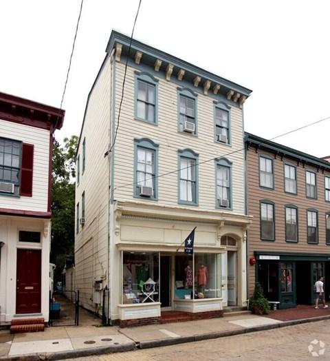 A white building with a red door and a black flag on the front.