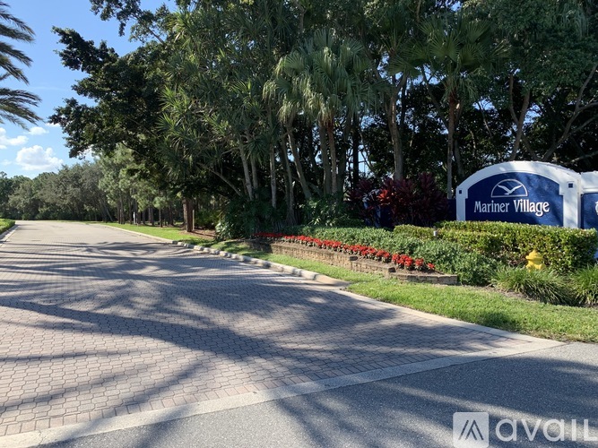 A street view of Mariner Village with a sign and trees.