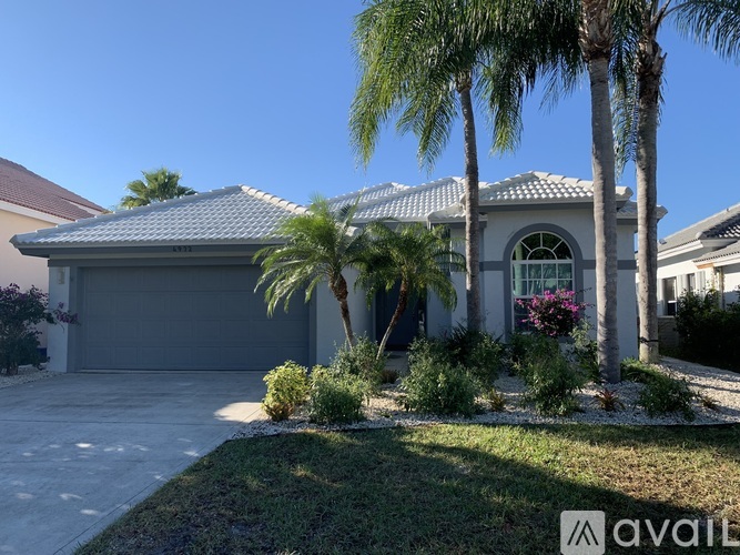 A house with a garage and a palm tree in front.