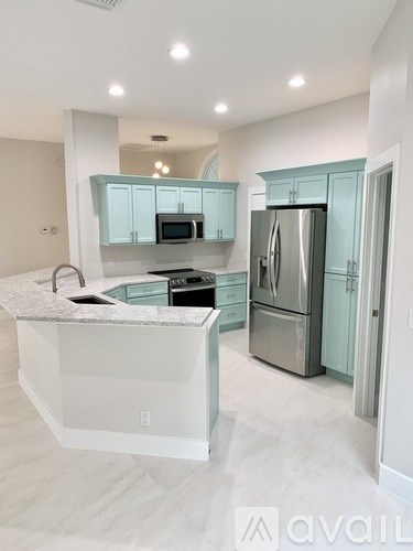 A kitchen with a refrigerator, microwave, and oven.