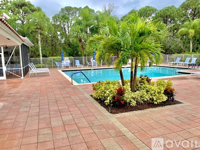 A pool surrounded by a brick patio and palm trees.