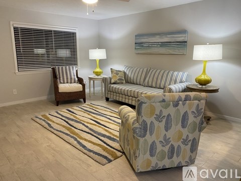 A living room with a striped couch, a chair, and a painting on the wall.