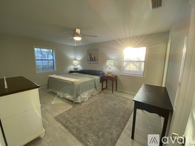 A bedroom with a bed, a table, and a ceiling fan.