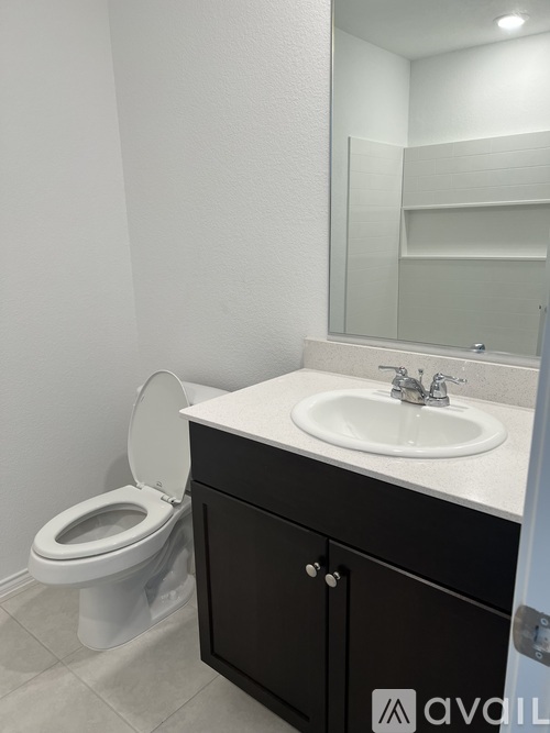 A bathroom with a toilet, sink and mirror.