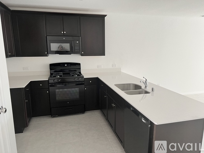 A kitchen with black cabinets and a stove top oven.