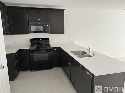 A kitchen with black cabinets and a stove top oven.
