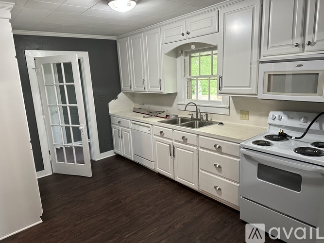 A kitchen with white cabinets and a stove top oven.
