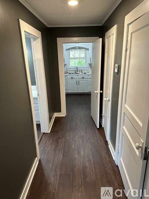 A hallway with a mirror on the left and a kitchen in the distance.