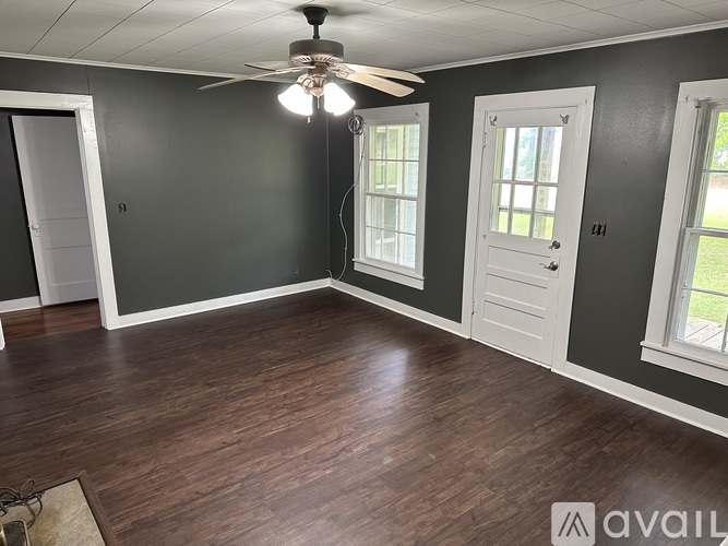 A room with a ceiling fan and two windows.