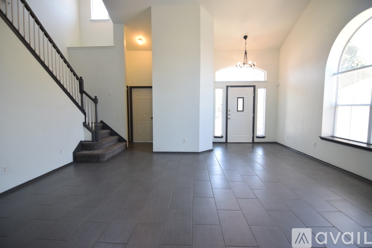 A spacious room with a staircase and a chandelier.