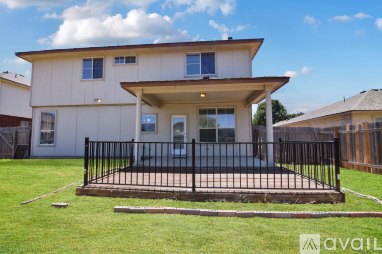 A house with a white and beige exterior and a black fence.