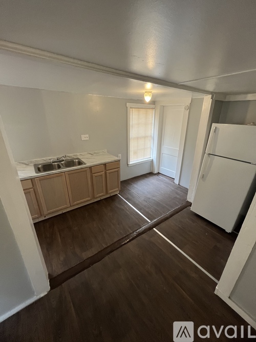 A kitchen with a white fridge and wooden floors.